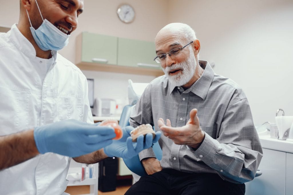 Man with dentist looking at a denture