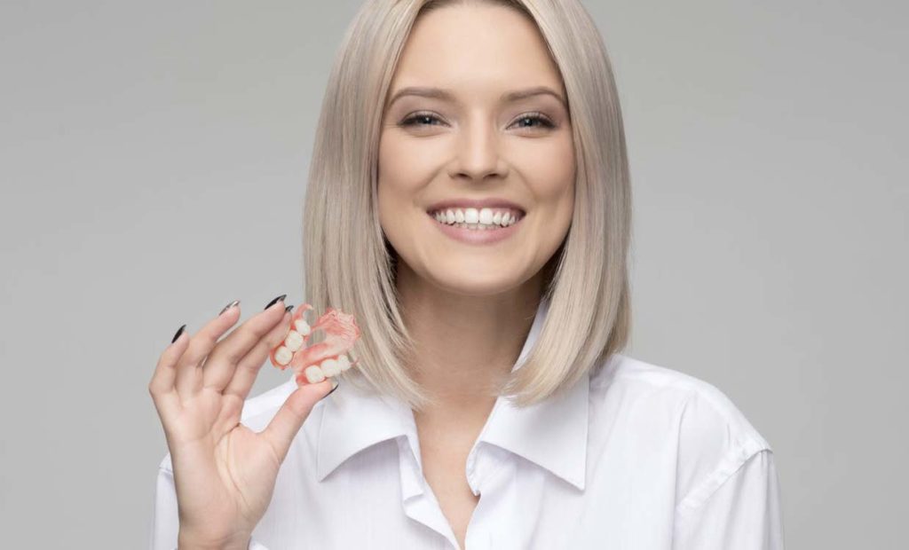 Lady holding partial false teeth and dentures